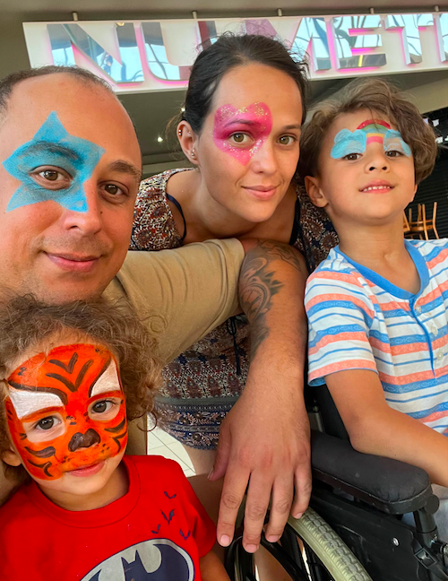Dino, father, Courtney, mother with Elijah and Isaiah with their faces painted. The parents have a big star over their one eye, Elijah has clouds and a rainbow. Isaiah has a tiger.